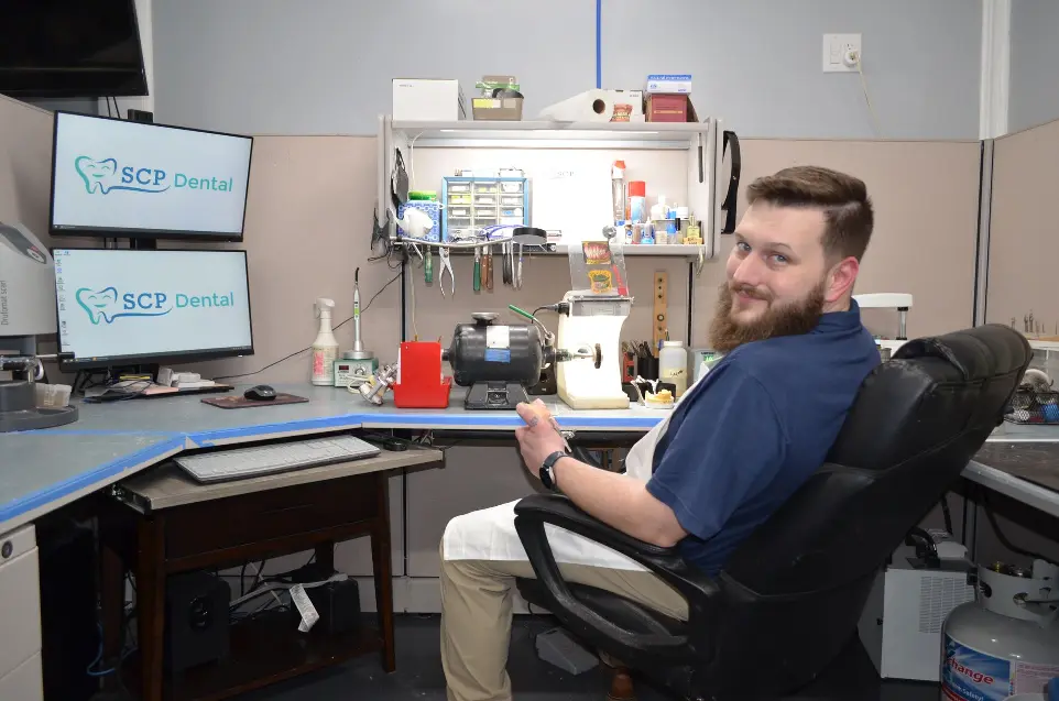 Clay Sitting at Work bench Case in Hand Smiling
